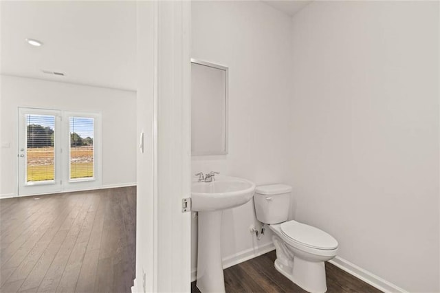 bathroom featuring hardwood / wood-style floors, baseboards, and toilet