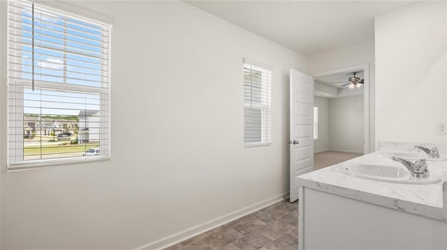 bathroom featuring baseboards, ceiling fan, and double vanity