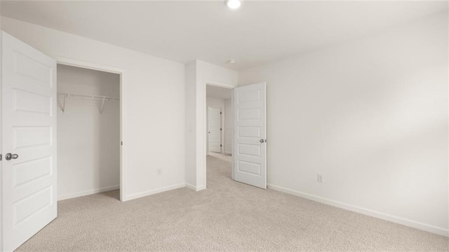 unfurnished bedroom with light carpet, baseboards, and a closet