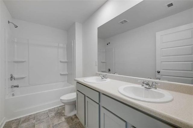 full bathroom with toilet, tub / shower combination, double vanity, and stone finish flooring