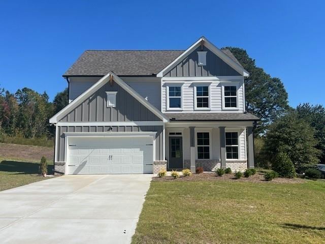 craftsman-style house with brick siding, a porch, board and batten siding, a front yard, and driveway