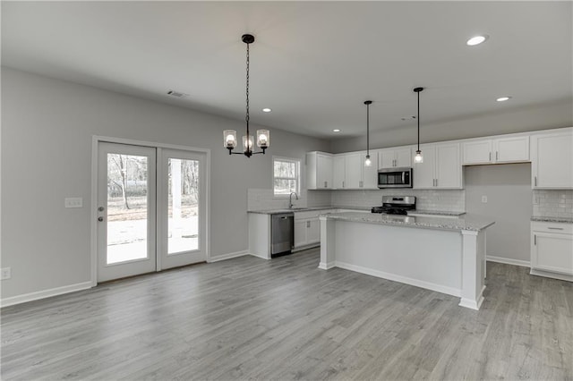 kitchen with visible vents, white cabinets, decorative backsplash, appliances with stainless steel finishes, and light wood-style floors