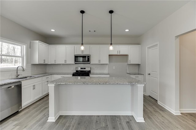 kitchen featuring stainless steel appliances, a center island, white cabinetry, and a sink