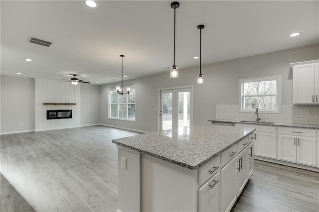 kitchen with a large fireplace, a sink, visible vents, backsplash, and a center island