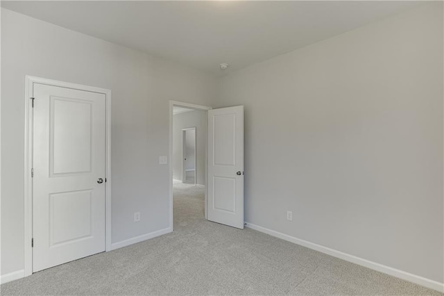 unfurnished bedroom with light colored carpet and baseboards