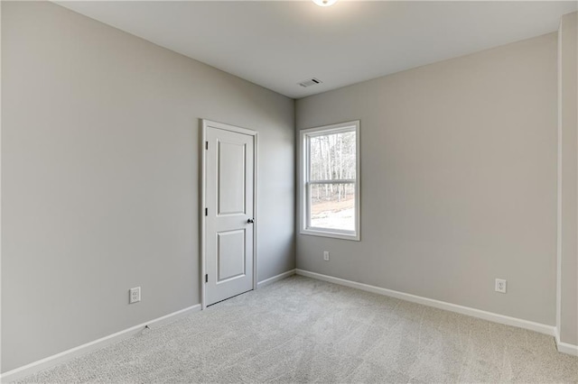 unfurnished room with light carpet, visible vents, and baseboards