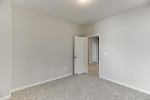 empty room featuring light colored carpet and baseboards