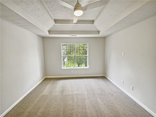 carpeted empty room with a textured ceiling, a tray ceiling, and ceiling fan