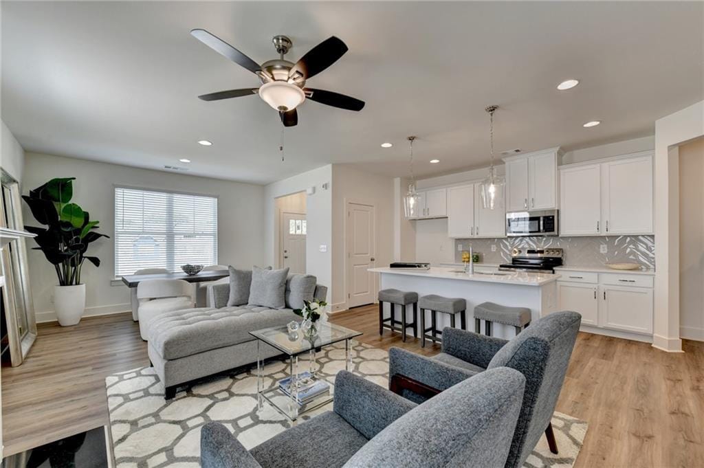 living room with ceiling fan and light hardwood / wood-style floors