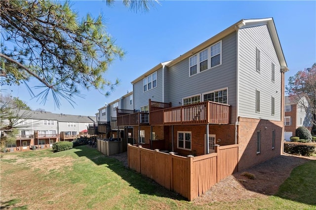 back of house featuring a deck, a yard, brick siding, and a residential view