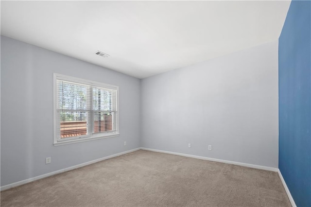 carpeted spare room featuring visible vents and baseboards