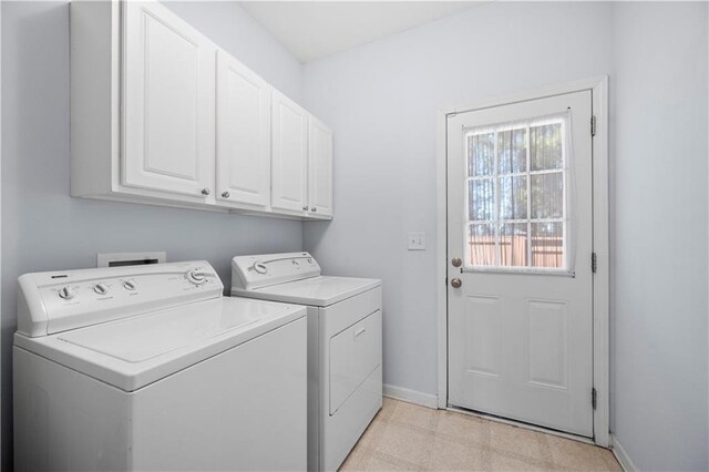 clothes washing area with baseboards, cabinet space, light floors, and washing machine and dryer