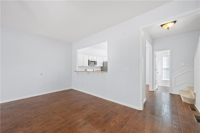 empty room featuring stairway, dark wood-style floors, and baseboards