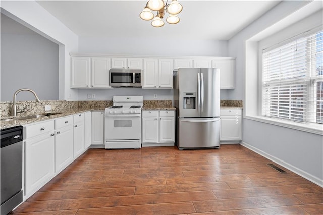 kitchen featuring visible vents, a sink, stainless steel appliances, dark wood-type flooring, and white cabinets