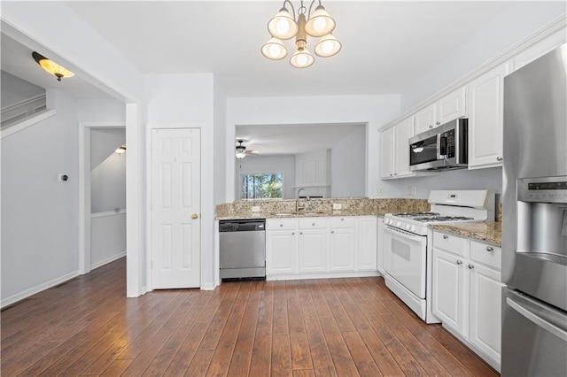 kitchen with light stone countertops, stainless steel appliances, dark wood-style floors, white cabinetry, and a sink