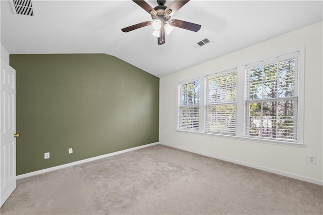 empty room with lofted ceiling, visible vents, and light carpet