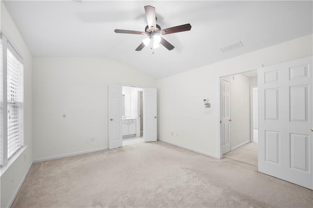 unfurnished bedroom with visible vents, light colored carpet, baseboards, and lofted ceiling