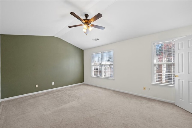 spare room featuring visible vents, baseboards, lofted ceiling, light carpet, and a ceiling fan