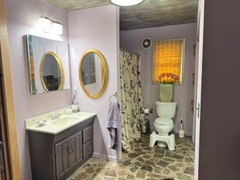 full bath with stone finish floor, vanity, toilet, a shower with shower curtain, and baseboards
