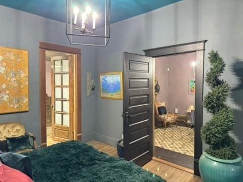 bedroom featuring baseboards, a chandelier, and wood finished floors