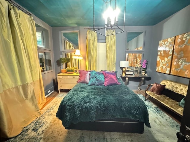 bedroom featuring a chandelier, wood finished floors, and baseboards