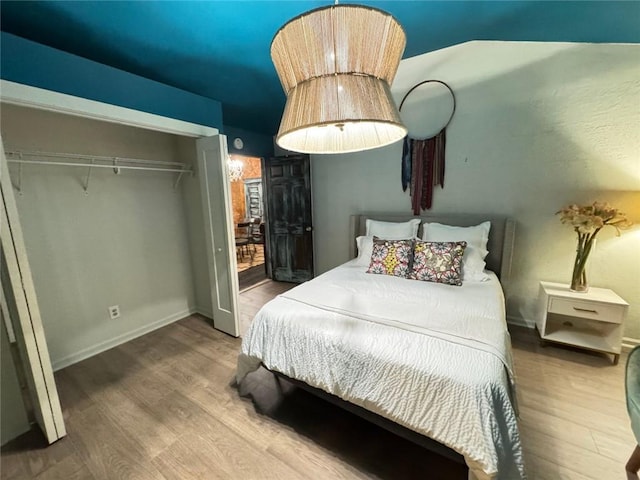 bedroom with a closet, baseboards, and wood finished floors