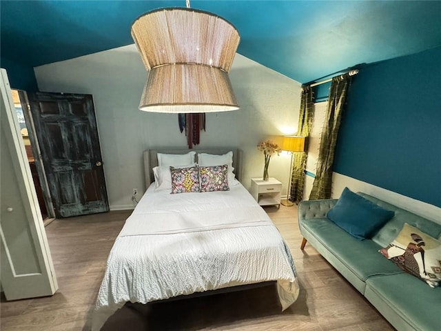 bedroom featuring wood finished floors and lofted ceiling