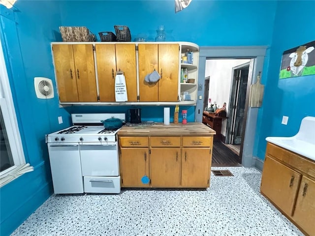 kitchen with brown cabinetry, visible vents, white range with gas cooktop, and open shelves