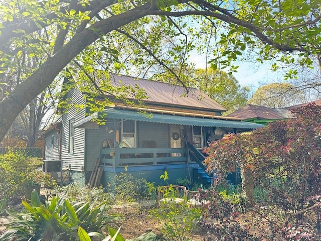 exterior space with stairs, metal roof, and covered porch
