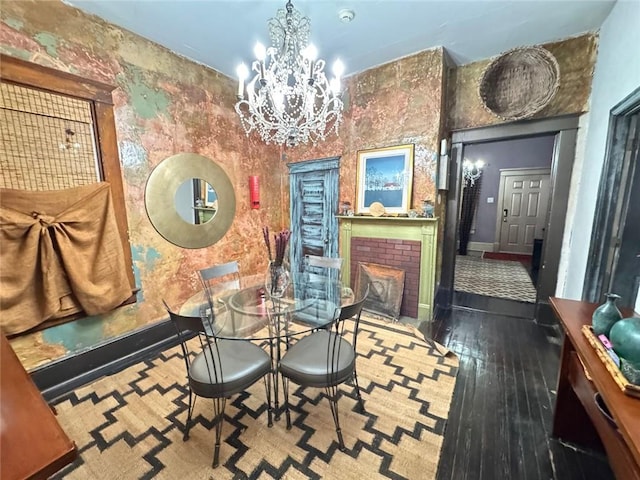 dining space featuring an inviting chandelier, wood-type flooring, and a brick fireplace