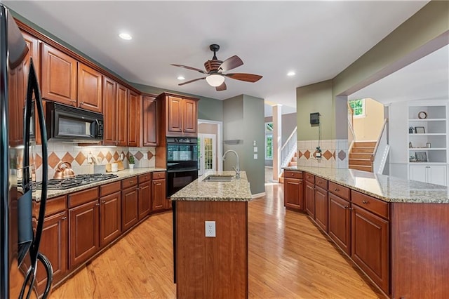 168 Eagle Pointe Dr, Dahlonega, GA 30533 - kitchen featuring black appliances, a sink, a kitchen island with sink, ceiling fan, and tasteful backsplash