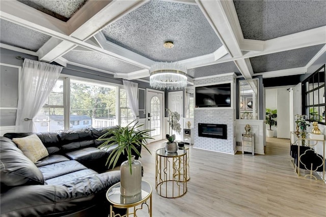 living room with beam ceiling, a large fireplace, wood-type flooring, a notable chandelier, and coffered ceiling