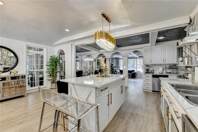 kitchen featuring white cabinetry, light wood-type flooring, dishwasher, decorative light fixtures, and a center island