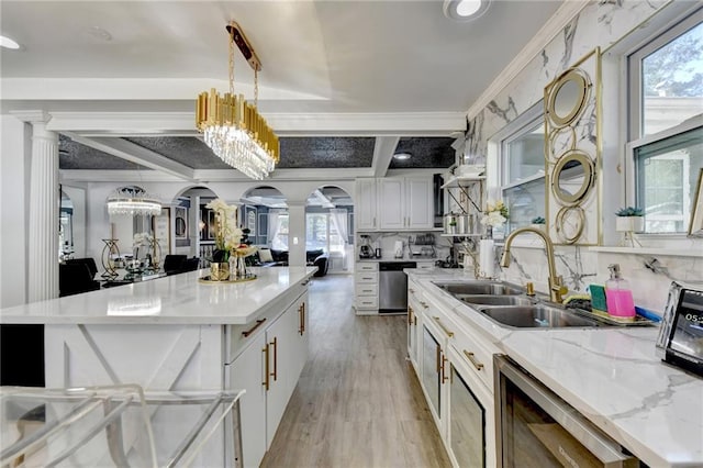 kitchen with a kitchen island, ornate columns, sink, decorative light fixtures, and white cabinets