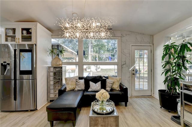 living room featuring a chandelier, light wood-type flooring, and vaulted ceiling