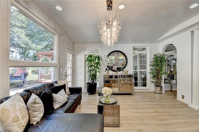 living room with a healthy amount of sunlight, a chandelier, and light wood-type flooring