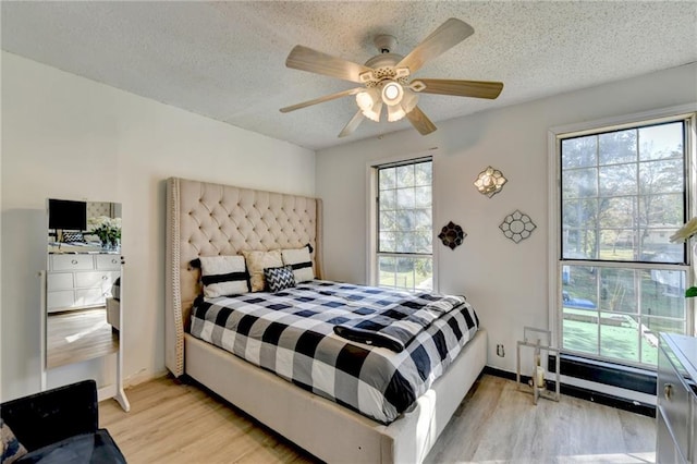 bedroom with ceiling fan, a textured ceiling, and light wood-type flooring