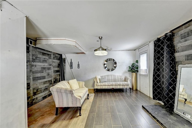 sitting room with ceiling fan, wood walls, and hardwood / wood-style floors