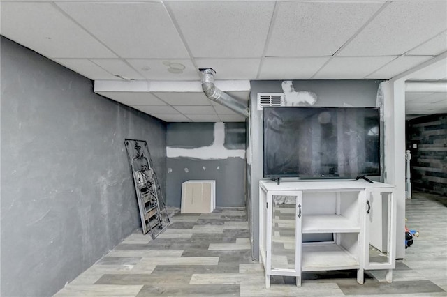 basement featuring a drop ceiling and wood-type flooring