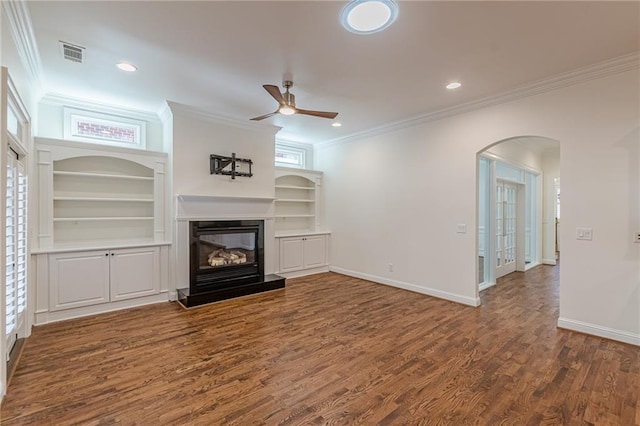 unfurnished living room featuring dark wood-type flooring, crown molding, built in shelves, and ceiling fan