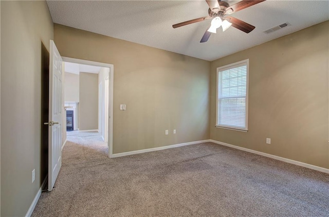 unfurnished room with ceiling fan, light colored carpet, and a textured ceiling