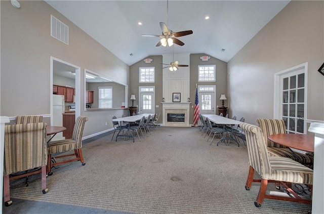 dining room with carpet flooring, high vaulted ceiling, and ceiling fan