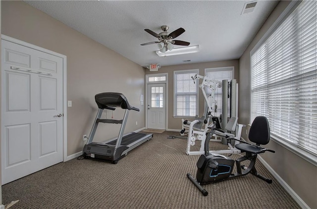 exercise room with ceiling fan, dark carpet, and a textured ceiling