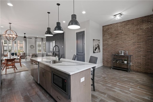 kitchen with pendant lighting, appliances with stainless steel finishes, sink, a chandelier, and a center island with sink