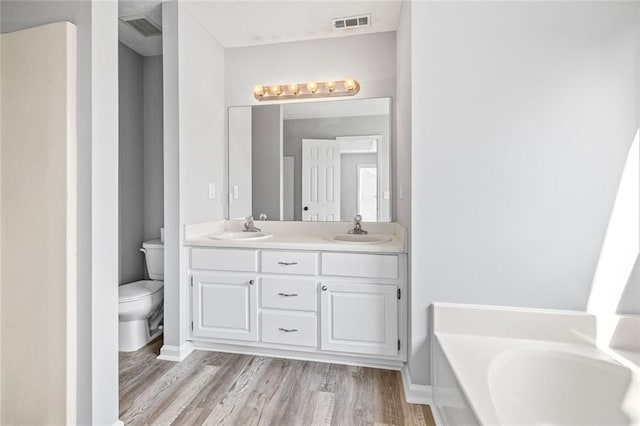630 River Mill Rd, Bethlehem, GA 30620 - bathroom featuring toilet, a garden tub, wood finished floors, and double vanity