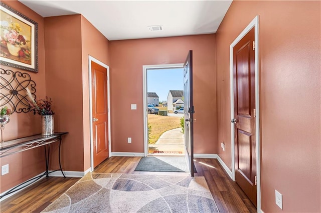 foyer entrance featuring dark wood-type flooring, visible vents, and baseboards