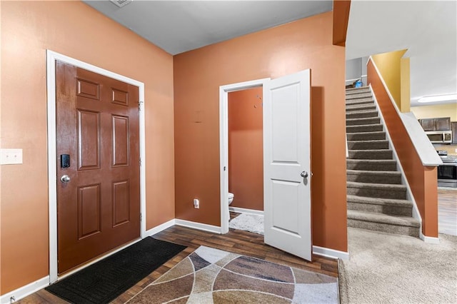 foyer entrance with stairs, wood finished floors, and baseboards