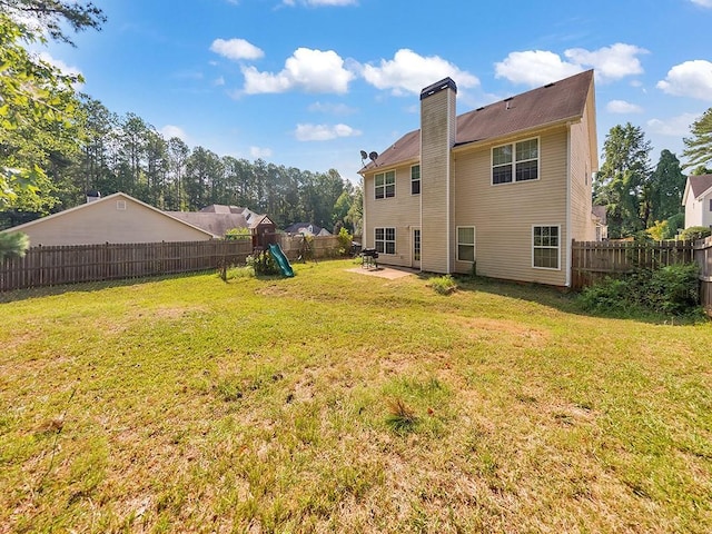 388 Oakhaven Way, Villa Rica, GA 30180 - rear view of house with a chimney, a patio, a fenced backyard, a playground, and a lawn
