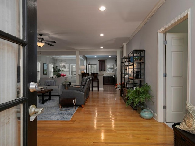 living room with crown molding, light hardwood / wood-style flooring, and ceiling fan with notable chandelier