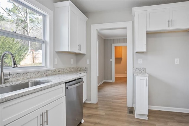 kitchen featuring white cabinetry, light wood-style flooring, a sink, baseboards, and dishwasher